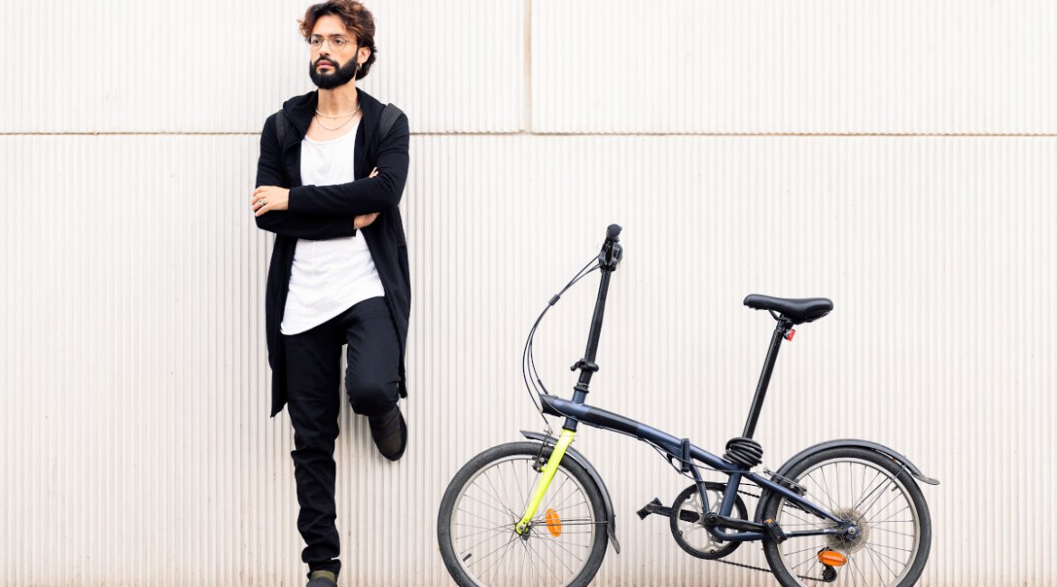 stylish man in a white wall next to folding bike